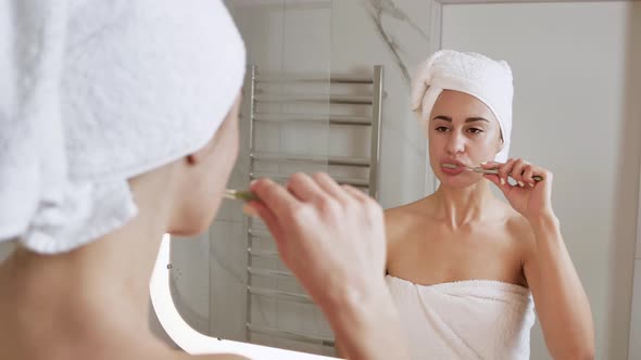 Attractive 25Aged Female Standing Near the Bathroom Mirror Brushing His Teeth