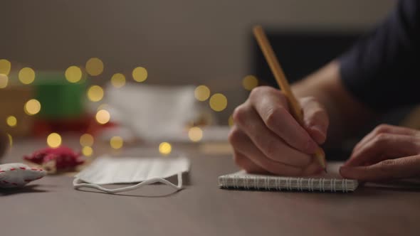 Slow Motion Orbit Shot Closeup Man Writes Shopping List Notepad Pencil Under Warm Light Evening