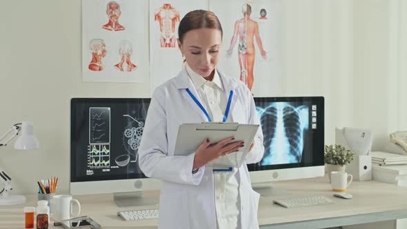 Portrait of Cheerful Female Doctor with Clipboard in Clinic