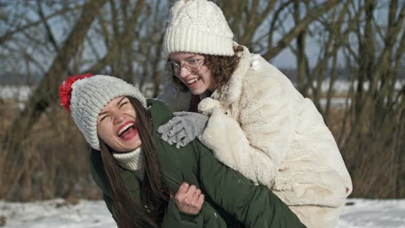 Mom and an Adult Daughter or Two Sisters are Having Fun During a Winter Walk and Someone is Throwing