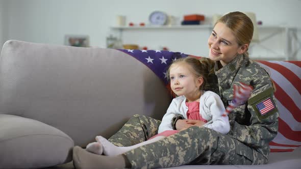 American Female Veteran and Little Daughter With Flag Watching Military March