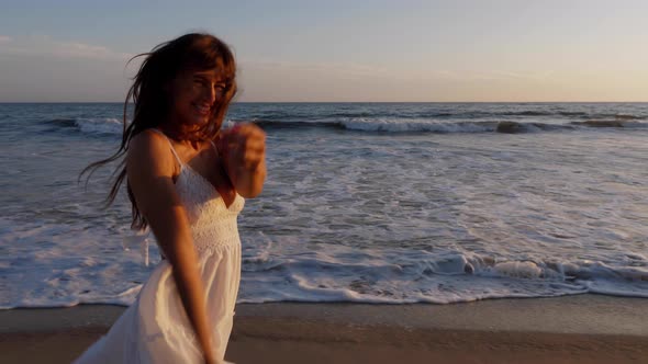 Beautiful woman in a white dress at the beach at sunset