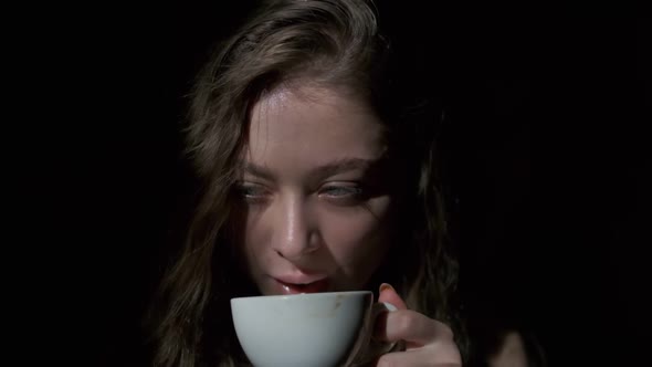 Close-up of girl drinking coffee with pleasure from a white cup