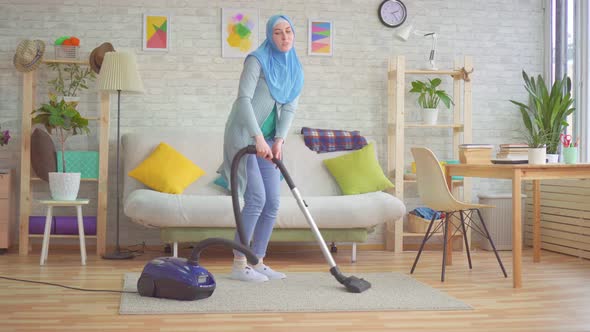 Muslim Woman in Hijab Vacuuming Carpet and Dancing