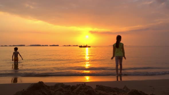 Silhouettes of Children Playing in the Ocean Waves