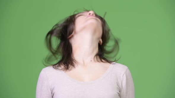 Young Beautiful Woman Flipping Hair Against Green Background