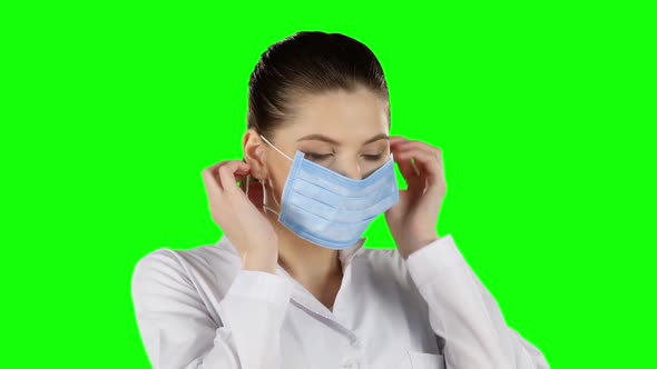 Young Doctor Putting on Health Mask. Green Screen. Closeup