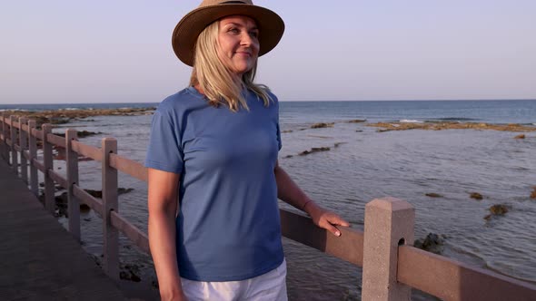 Middle aged woman wearing t-shirt and standing on by the sea