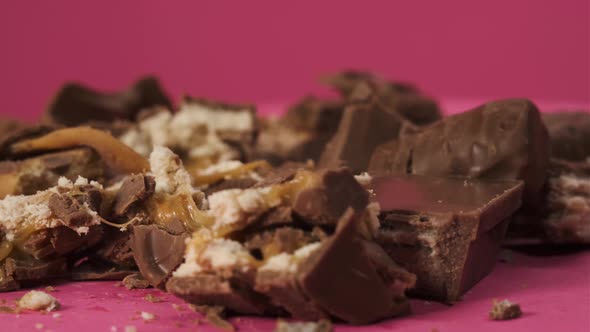 Mess with Delicious and Unhealthy Chocolate Bars Smashed Rotates on a Pink Background. Bitten Sweets