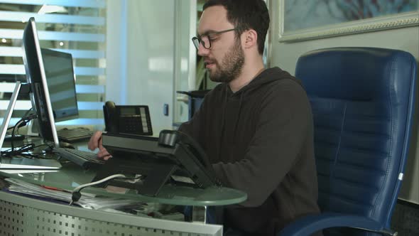 Side View of a Male Office Worker Working on Computer in a Bright Office