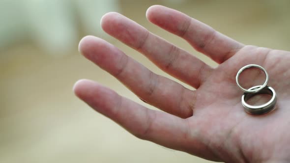 Groom is Holding Wedding Rings in Hands Closeup View