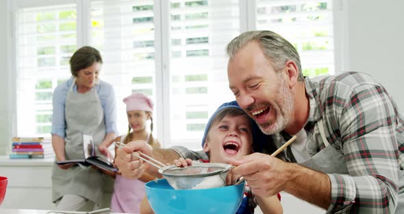 Father helping boy to filter flour using a strainer