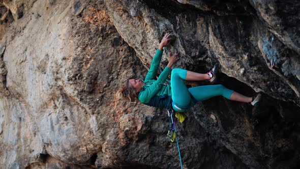 Strong Woman Rock Climber Climbs Hard Tough Rock Route on Very Overhanging Black Cliff in Turkey