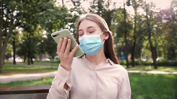 Portrait Girl in Mask Uses Smartphone Voice Recognition
