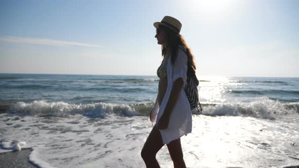 Young Female Hiker in Beachwear Walking Along Ocean Coast, Attractive Woman with Backpack Strolling