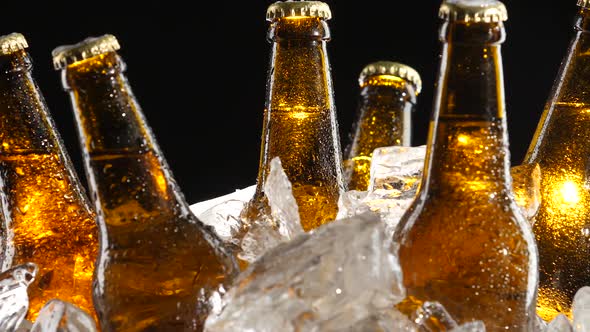 Condensate Flows Down the Brown Glass of Bottles From Beer, Black Background