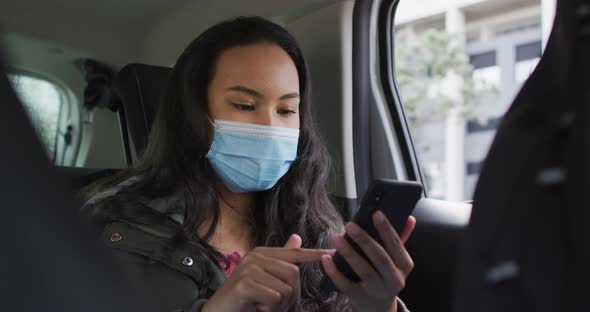 Asian woman wearing face mask using smartphone while sitting in the car