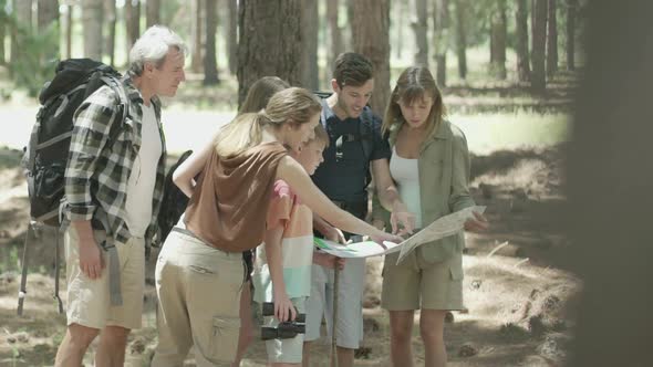 Family hiking through forest together pausing to check map