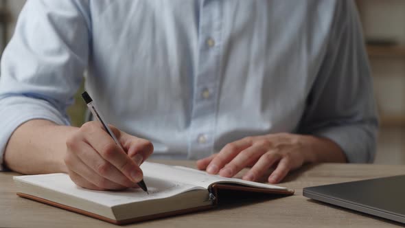 Close Up Shot of Man Sit at Desk Holds Pen Takes Notes in Diary Writes Startup Business Ideas and