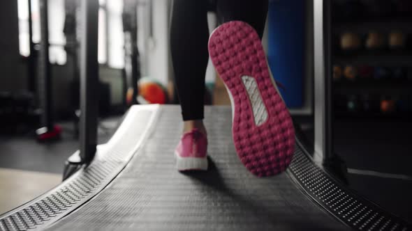 Close-up of sneakers: a girl athlete runs on a treadmill in the gym