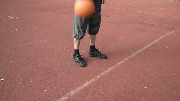 Amateur Basketball Player Practicing Ball Handling Skill Dribbling on Red Vinyl Covered Street Court