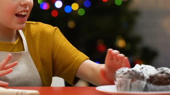 Child in Apron Stealing Cupcake From Festive Table, Tasting Dessert, Closeup