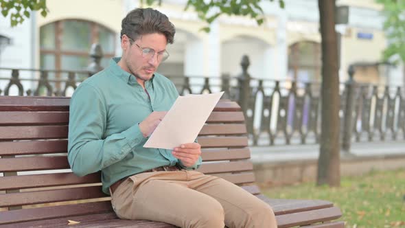 Man Reading Documents while Sitting on Bench Outdoor