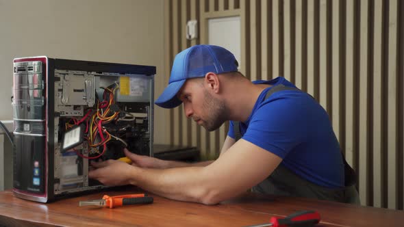 Man in Tshirt Repairs Computer System Unit with Screwdriver