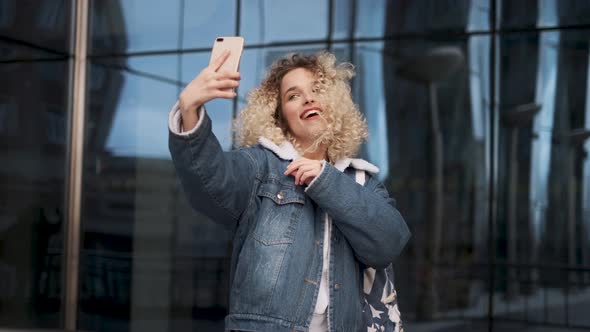 Beautiful Curly Girl Makes Selfie. Portrait of a Girl with a Charming Smile