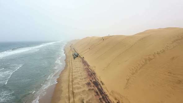 wide spiral shot of cars on a beach at the edge of the Namib desert