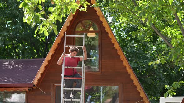 Professional builder climbing high steel ladder. Frame residential house under construction