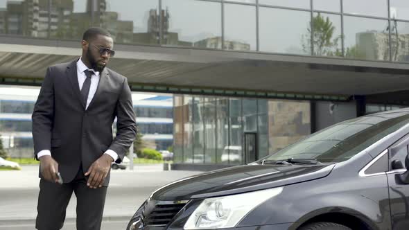 Personal Driver Waiting for His Boss Near Business Center, Talking on Phone