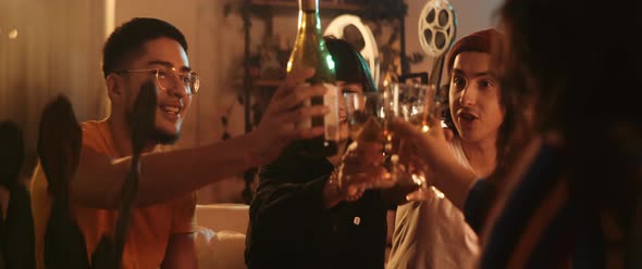 Young man pouring wine to his friends they cheer together with vintage projector in the back