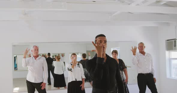 mixed race male dance teacher taking a ballroom dancing class at a dance studio