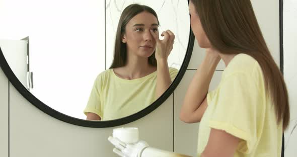 Woman with Prosthetic Arm Applying Cream Near Mirror at Home Girl with Disability Using Artificial