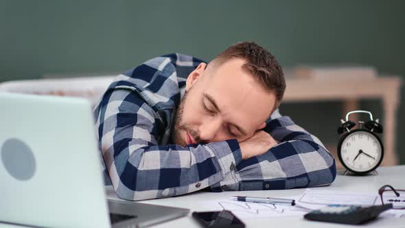 Tired Man Sleep on Table with Laptop and Documents at Workplace