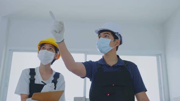 Asian construction man and woman worker people wear face mask examine renovation in house.