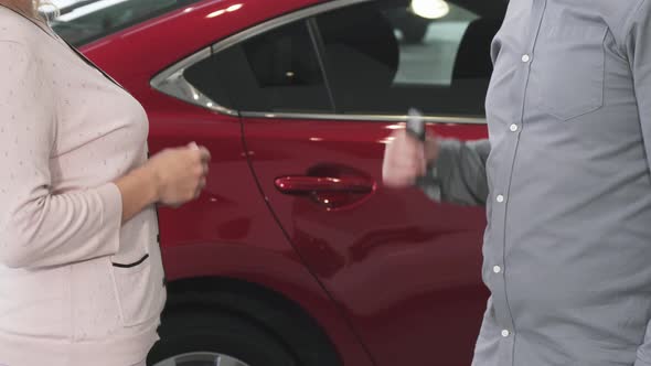 Cropped Shot of a Woman Receiving Keys To Her New Auto at the Dealership