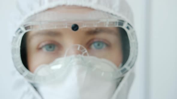 Zoom-in Portrait of Serious Woman Doctor Wearing Safety Uniform Mask, Suit and Respirator