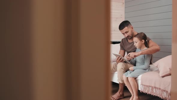 Cute Girl and her Father Using Tablet in Room