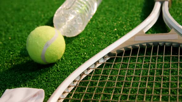 Tennis ball, racket, water bottle and hair band in tennis court 4k