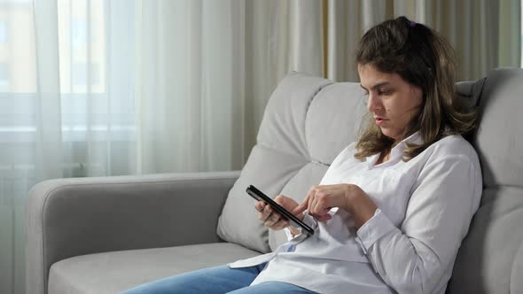 Disabled Woman Hardly Uses Mobile Phone Sitting on Sofa