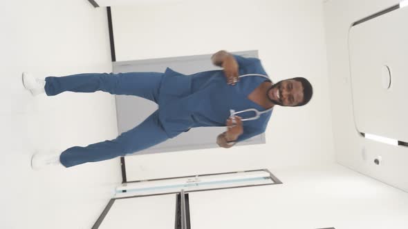 Portrait of Happy AfricanAmerican Doctor Performing a Fun Dance in the Hallway in Modern Clinic