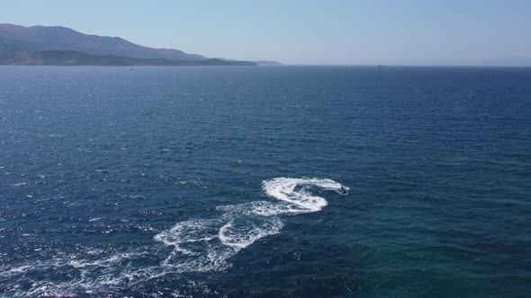 Aerial View Over Man Speeding On Jet Ski Tourist Attraction Exotic Tropical Island Shore Beach At