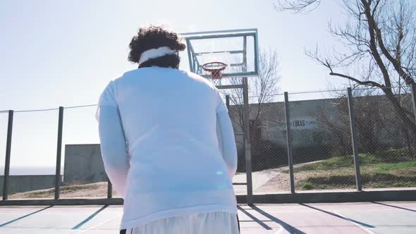 A Young Basketball Player Scoring a Ball While Playing Basketball on Outdoor Court