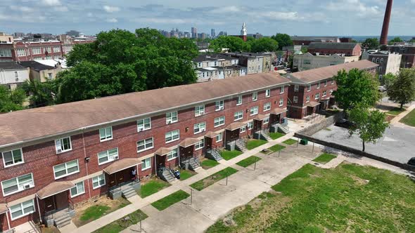 Red brick apartment building in urban America. City skyline in distance on sunny day. Poverty and lo