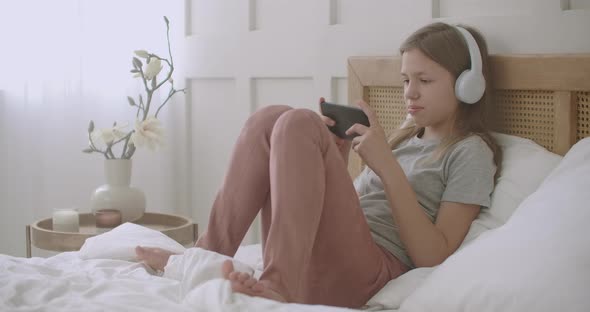 Child Girl Is Using Smartphone, Playing Game Online After Waking Up in Sunday Morning, Internet