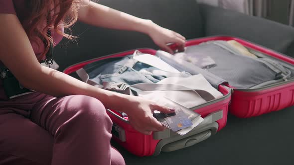 Women are packing a suitcase for travel trip with hold passport and credit card