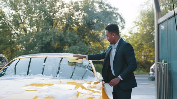 Handsome Young African American Businessman Cleaning His Car Windscreen with