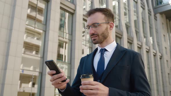 Portrait of Businessman in Formal Suit Standing with Coffee and Mobile Phone Outdoors at Street